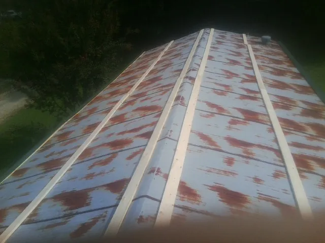 Rusted metal roof panels with new wood purlins before replacement — Storm Damage Roof Repair in Longmont by Roofing Brothers
