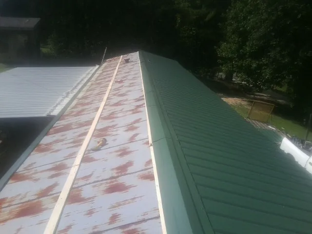 Old rusted panels beside newly installed green metal roofing — Wind Damage Roof Repair by Roofing Brothers in Longmont