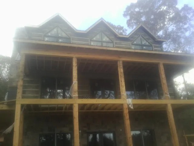 Dormers and porch framing on a large log home under construction — Roof Coating work by our crew in Longmont