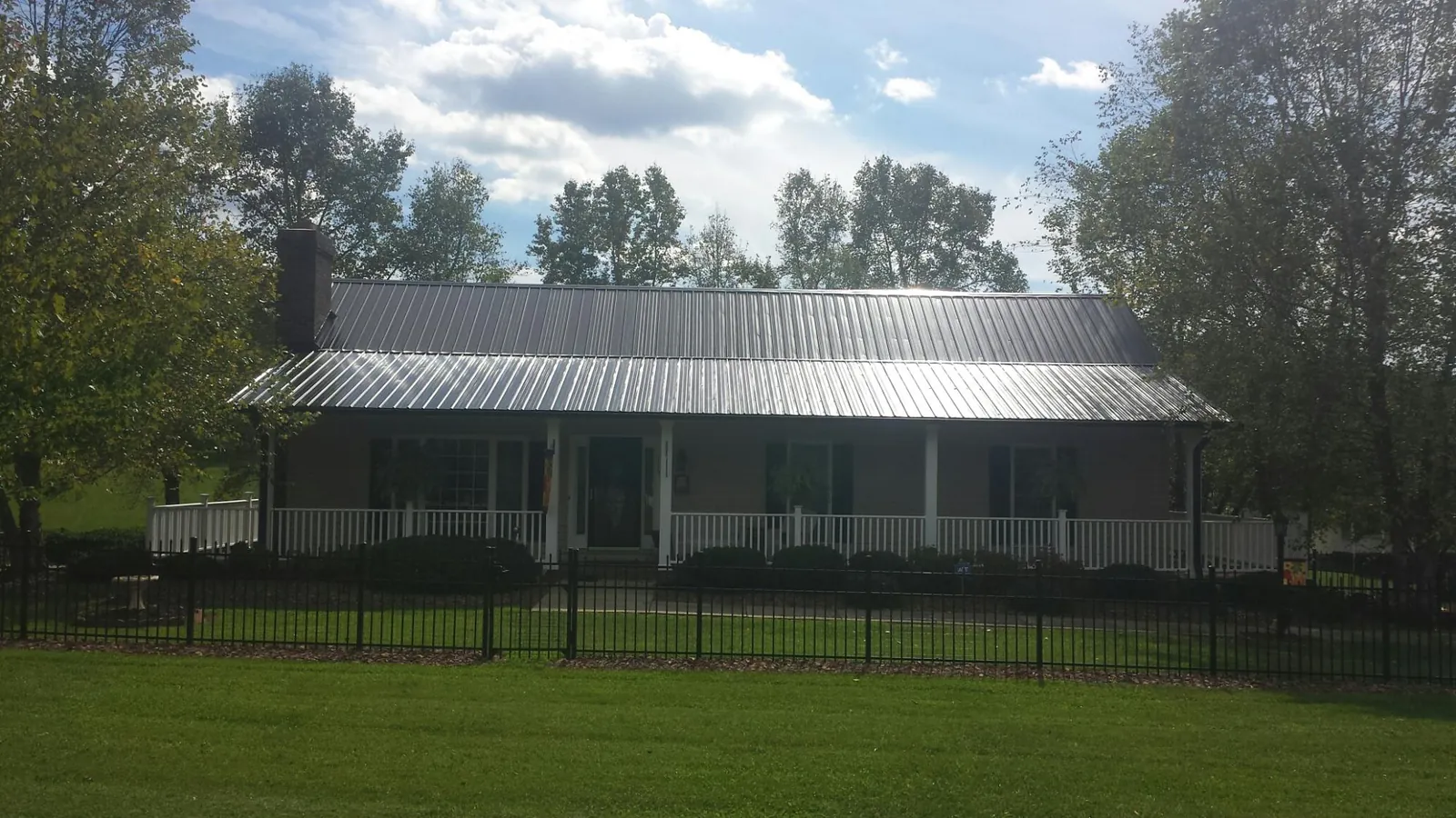 Gray metal roof on a brick ranch with a full width front porch — Gutter Guard Installation work by our crew in Longmont