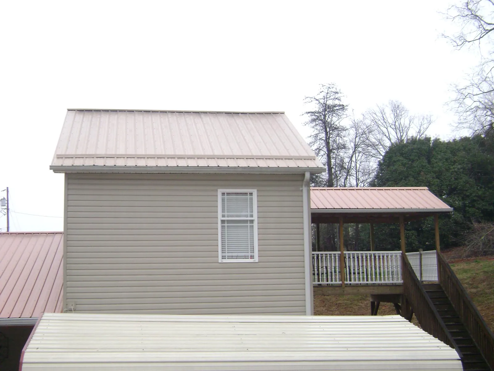 Tan metal roofs on a two story addition and attached porch, from a Roof Replacement job in Longmont