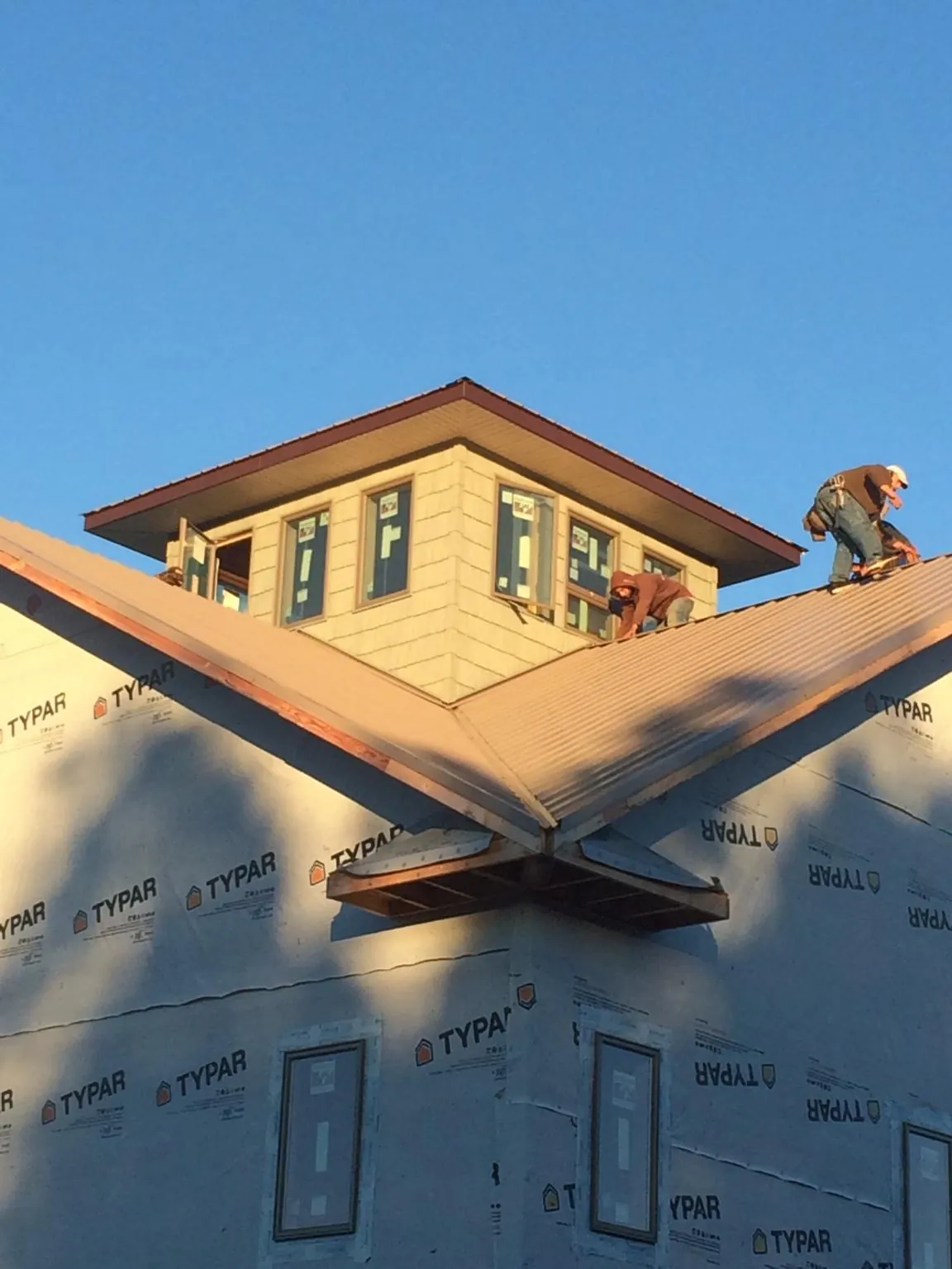 Roofers working around a rooftop cupola on a new metal roof at sunset — Roof Waterproofing in Longmont by Roofing Brothers